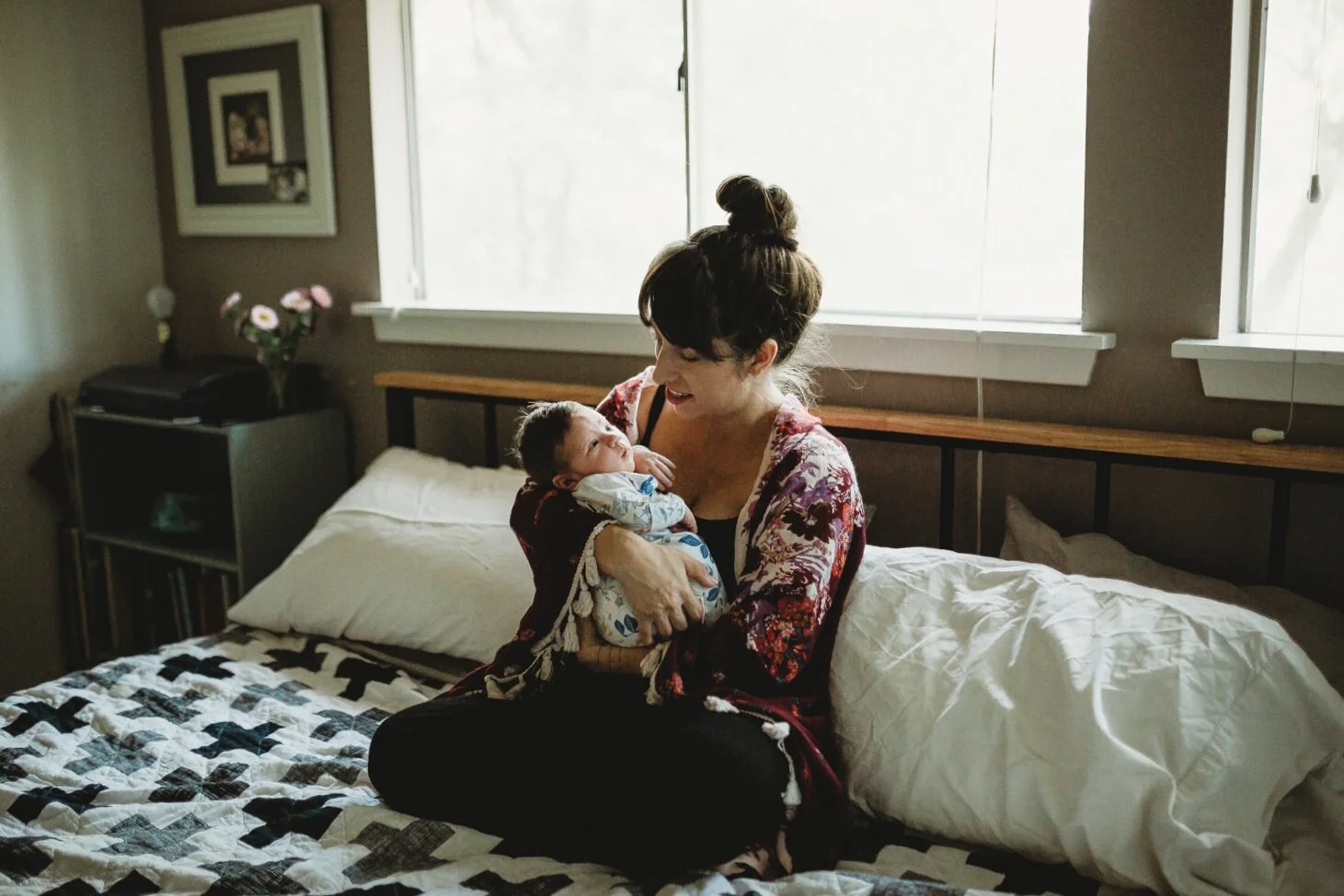 Sara Triana holding her newborn daughter by a bright window